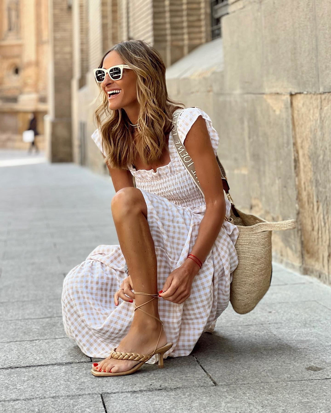Woman model in a smocked gingham maxi dress on a clean background.