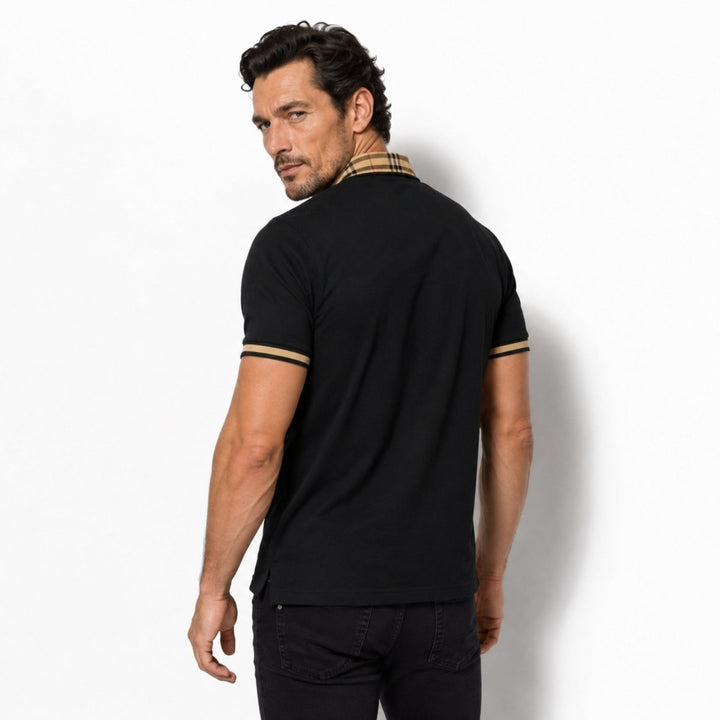  Model wearing a navy polo shirt with white buttons and patterned collar on a plain background.