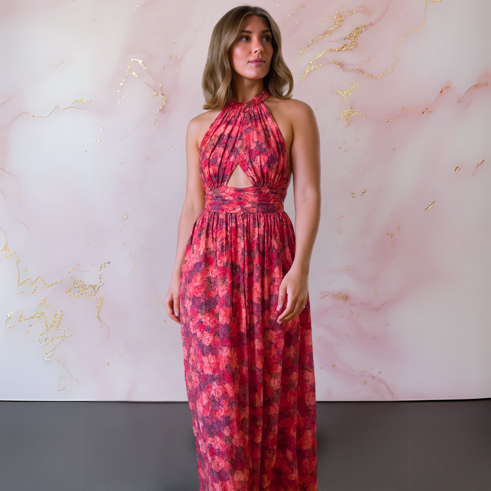 Woman styled in a long floral formal dress posing on a plain background.