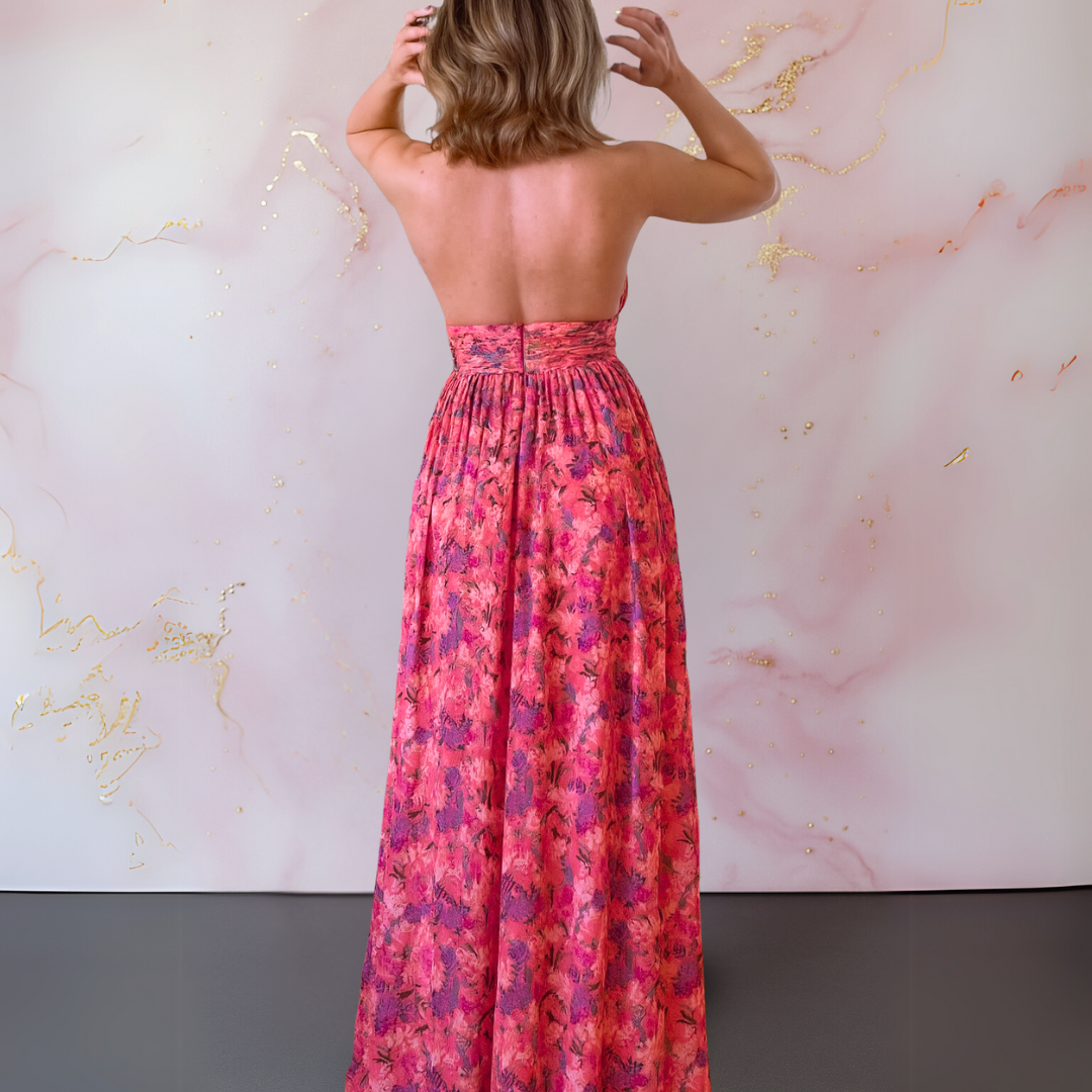 Female in a flowing floral evening dress with a graceful silhouette on a plain background, back view