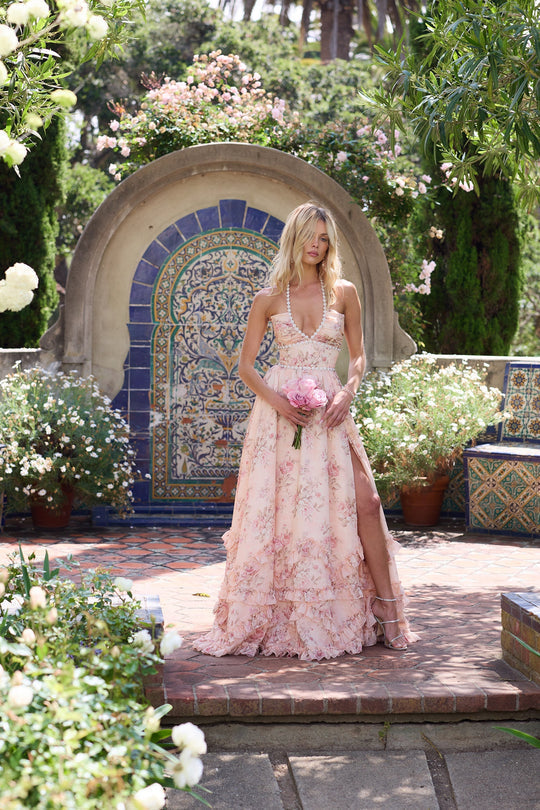 Feminine formal dress with halter neckline and floral pattern on a plain background.