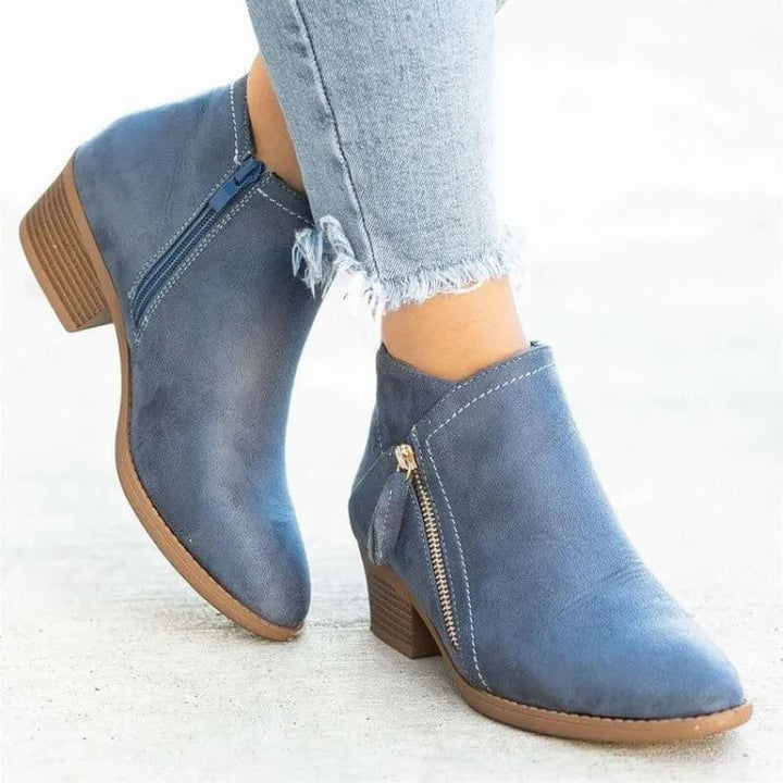 Blue ankle boots with brown soles worn with light blue jeans on a white background