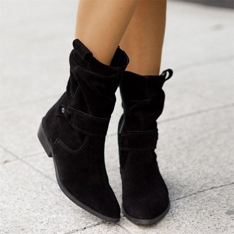Black boots worn by a person on a light gray pavement background