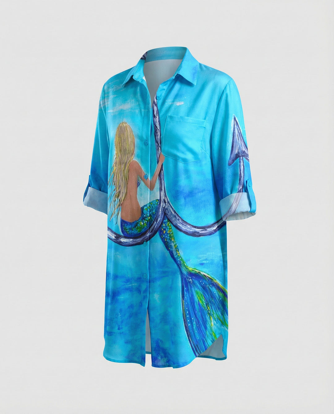 Woman showcasing a long summer blouse with an ocean motif against a plain background.