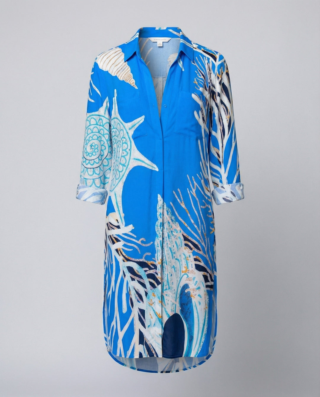 Woman in a lightweight longline beach shirt featuring a colourful marine-themed design on a plain background.