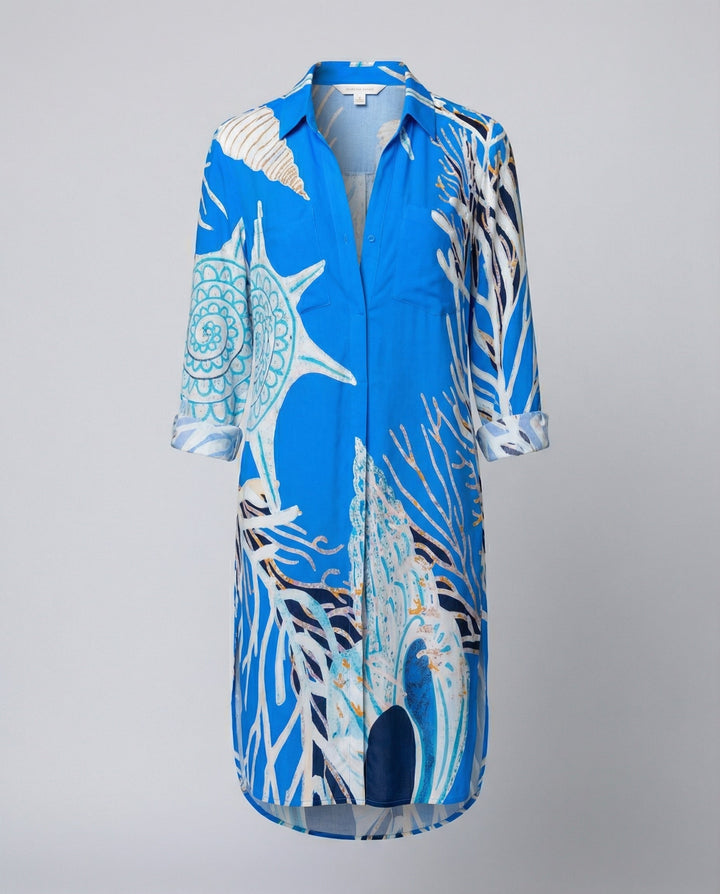 Woman in a lightweight longline beach shirt featuring a colourful marine-themed design on a plain background.