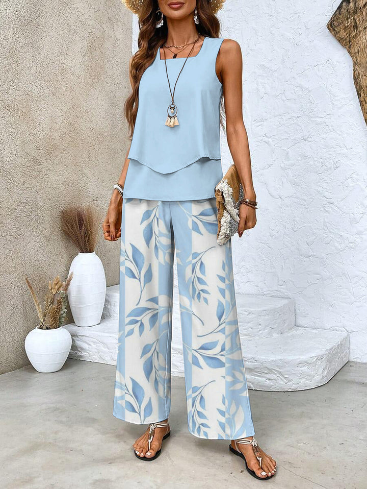 Female wearing a sleeveless layered top with wide-leg pants against a plain background.