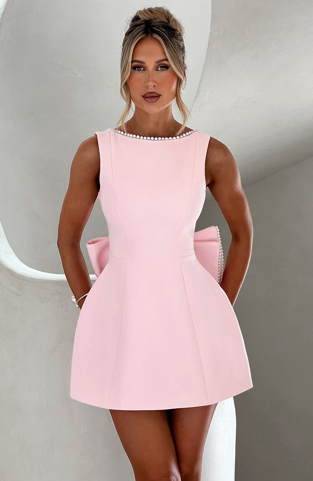 Female model wearing a structured mini dress against a plain background.