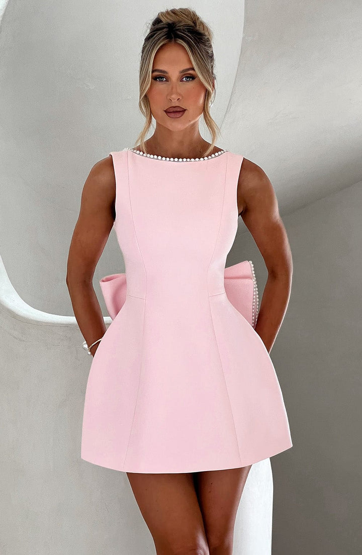 Female model wearing a structured mini dress against a plain background.