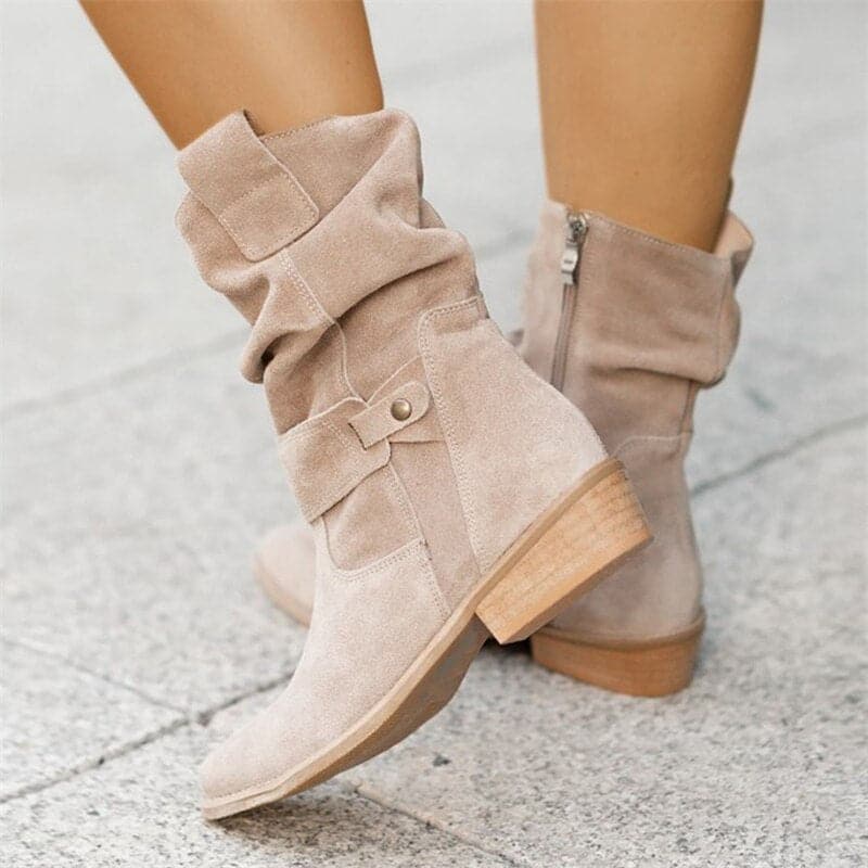 Beige boots with a button detail on a light gray pavement background