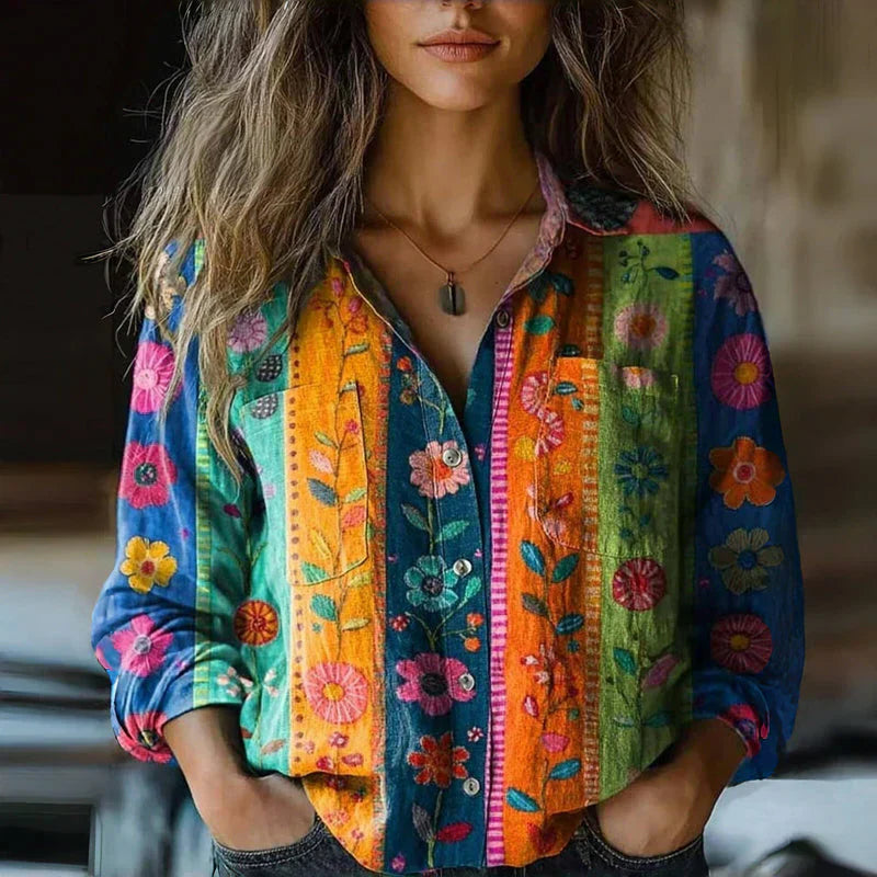 Woman model in a bold patterned blouse with button front detail on a plain background.
