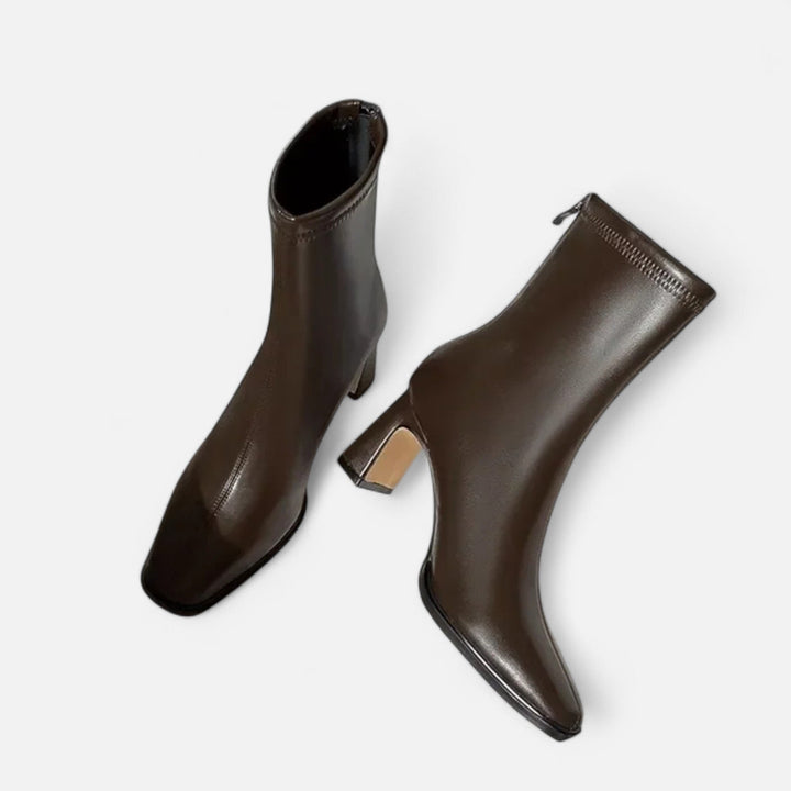 Mminimalist ankle boots with a square toe on a plain background.