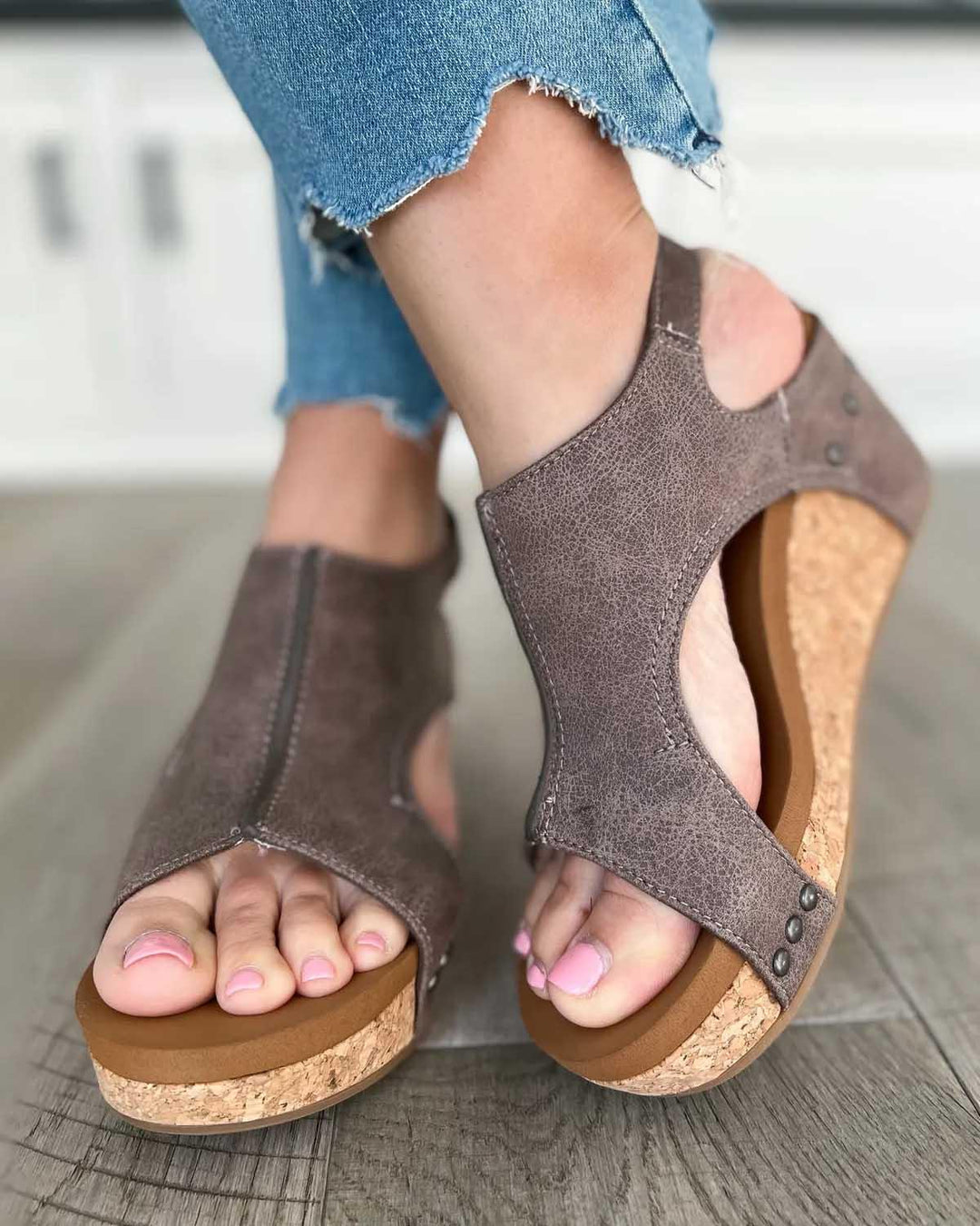 Foot model standing wearing hiking sandals on gray floor scene
