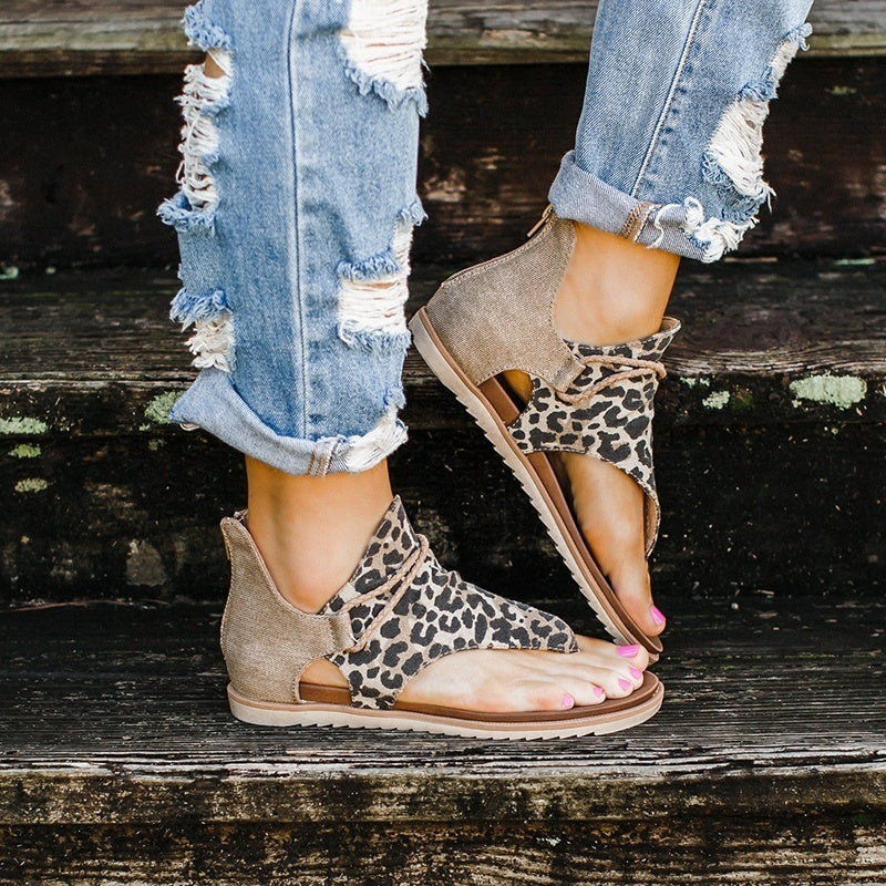 Side angle of foot in stylish sandals on beige background.
