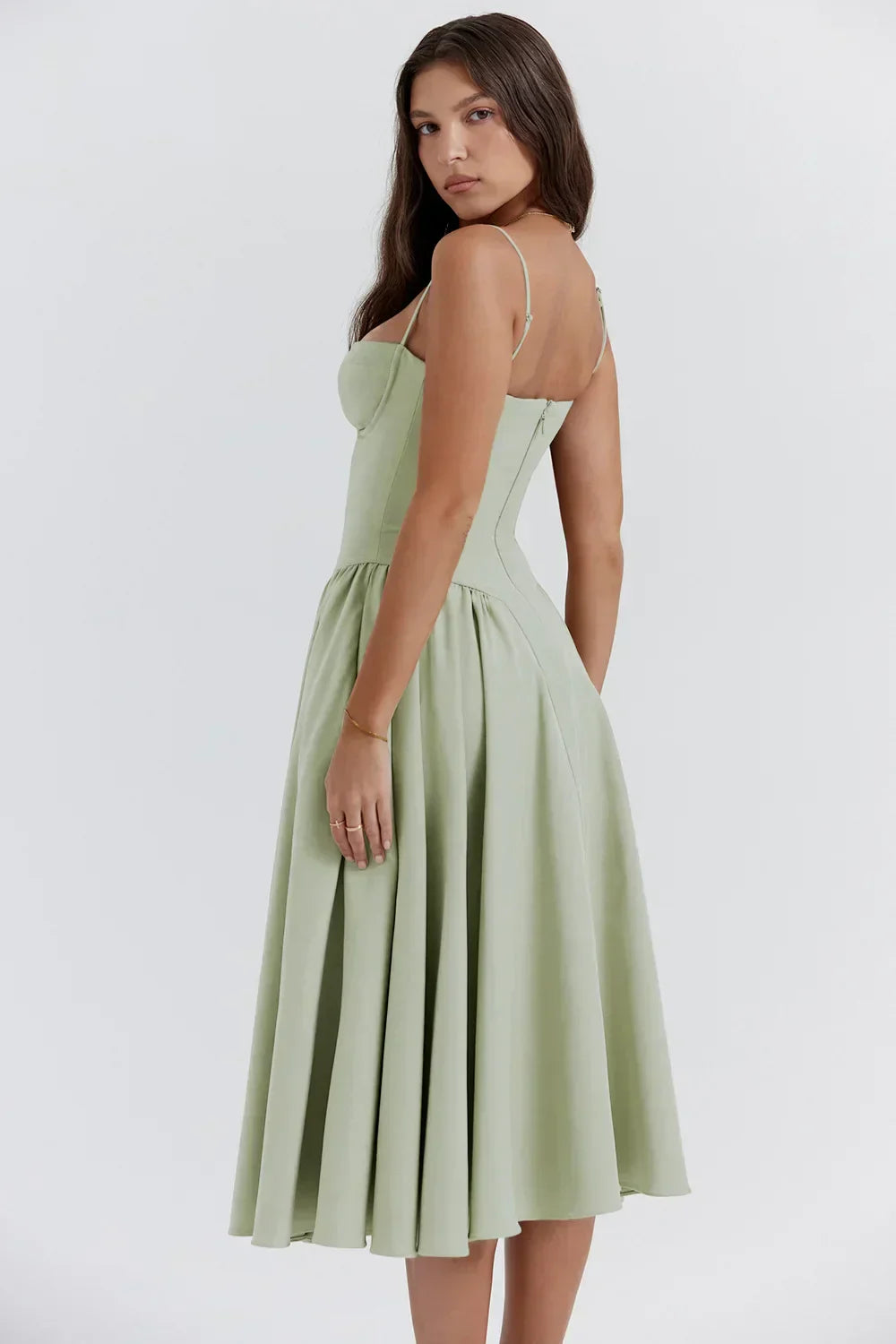 Woman posing in a sleeveless pleated midi dress against a plain background
