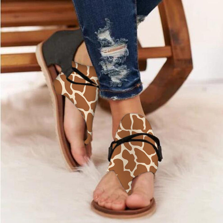 Foot in summer sandals with lifted heel on beige background.