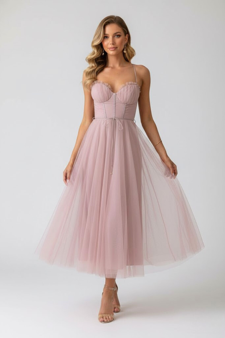 Woman wearing layered tulle dress on plain gray background front.