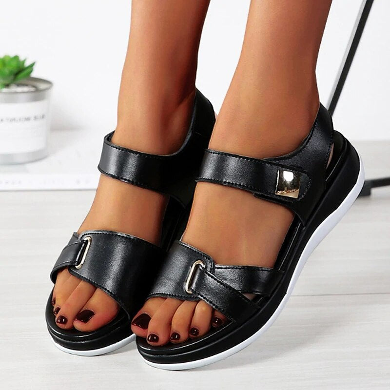Close-up front angle black sandals worn by foot model gray background