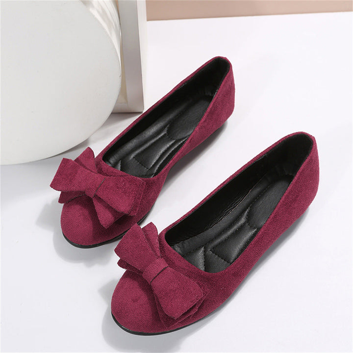 Pair of maroon shoes with bow details on a white background