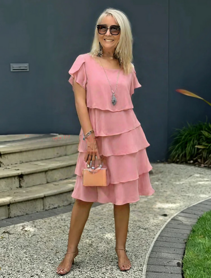  Woman showcasing a layered skirt midi dress on a plain background.