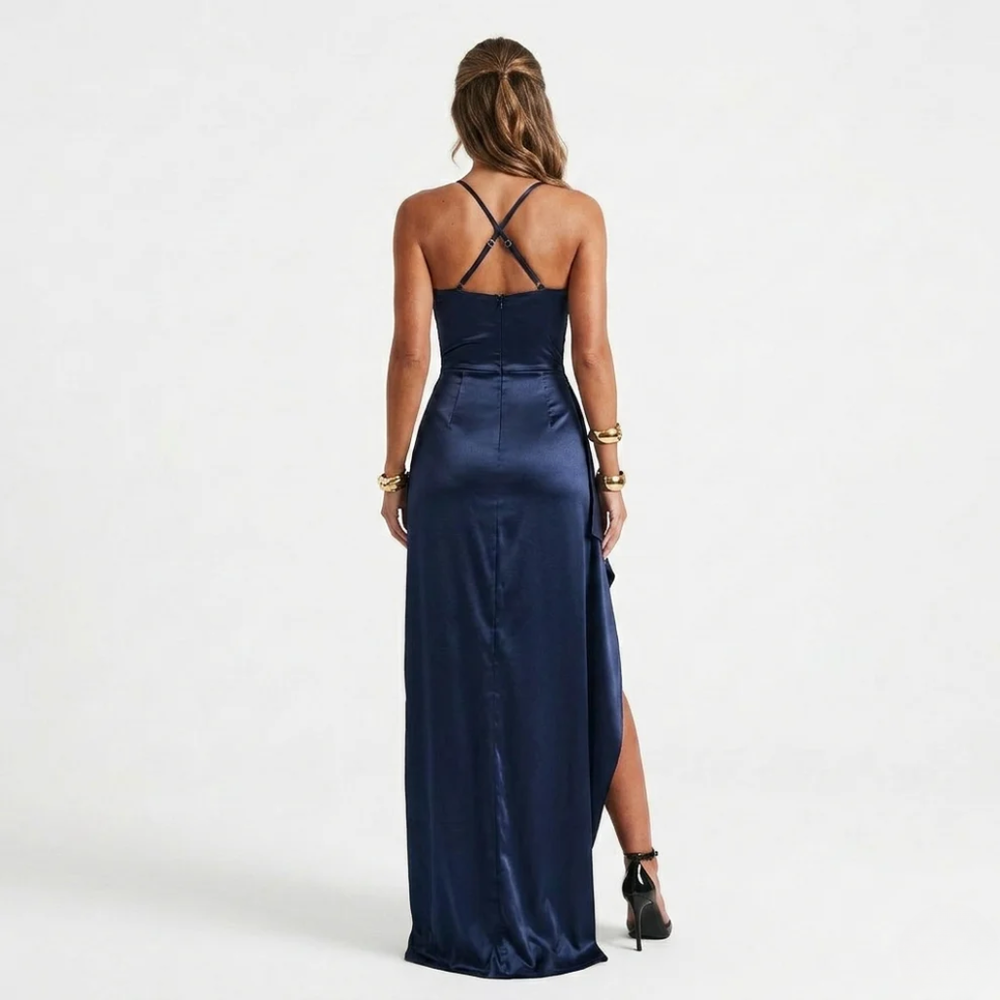 Woman posing in a sleeveless evening maxi dress with lace-up back styling on a plain background.