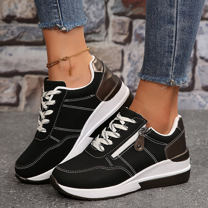 Lace-up everyday black trainer isolated against stone grey background