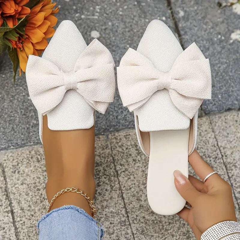 Foot model wearing elegant mules against stone gray backdrop
