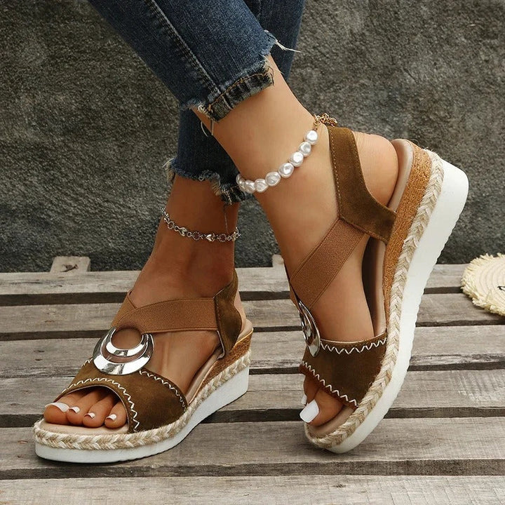 Foot wearing elegant wedge sandal from side, wooden background backdrop.