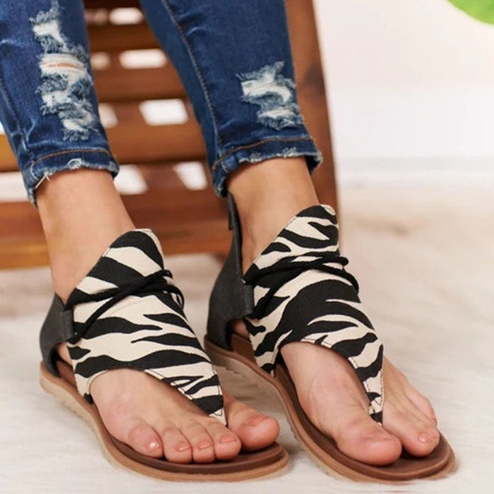 Foot wearing elegant summer sandals front view on plain beige background.