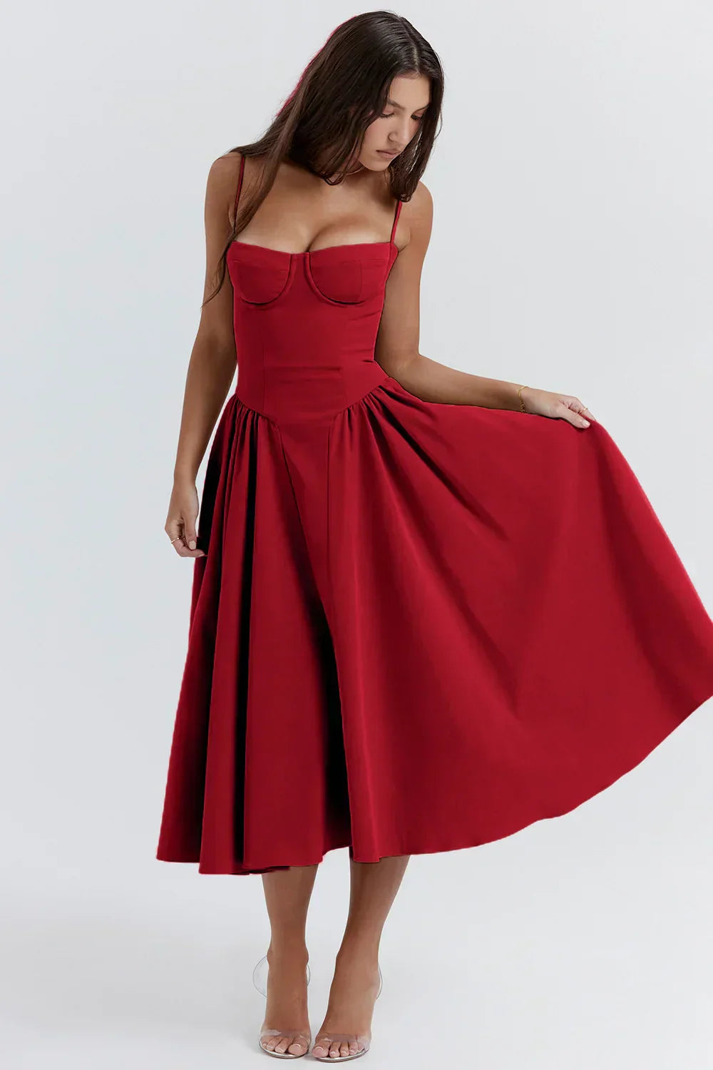 Woman wearing a feminine sleeveless midi dress on a plain background
