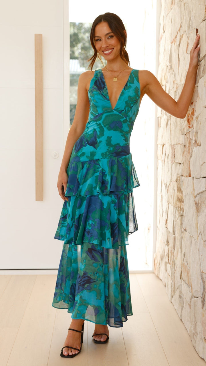 Model posing front in flowing floral dress block background