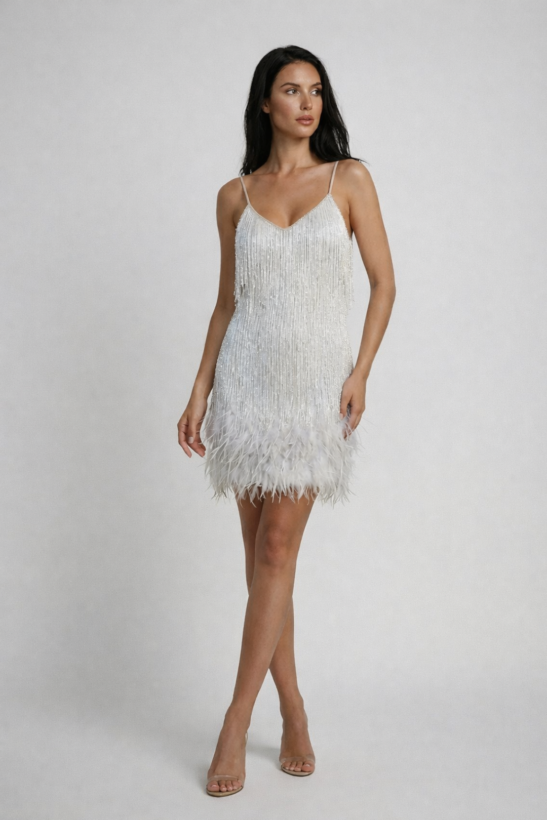 Model in a party mini dress with layered fringe movement on a plain background.