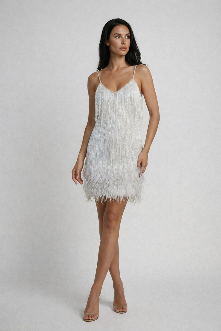 Model in a party mini dress with layered fringe movement on a plain background.
