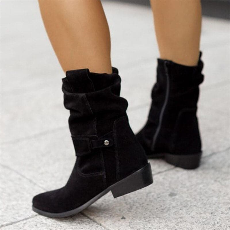 Black boots worn on a light gray pavement background