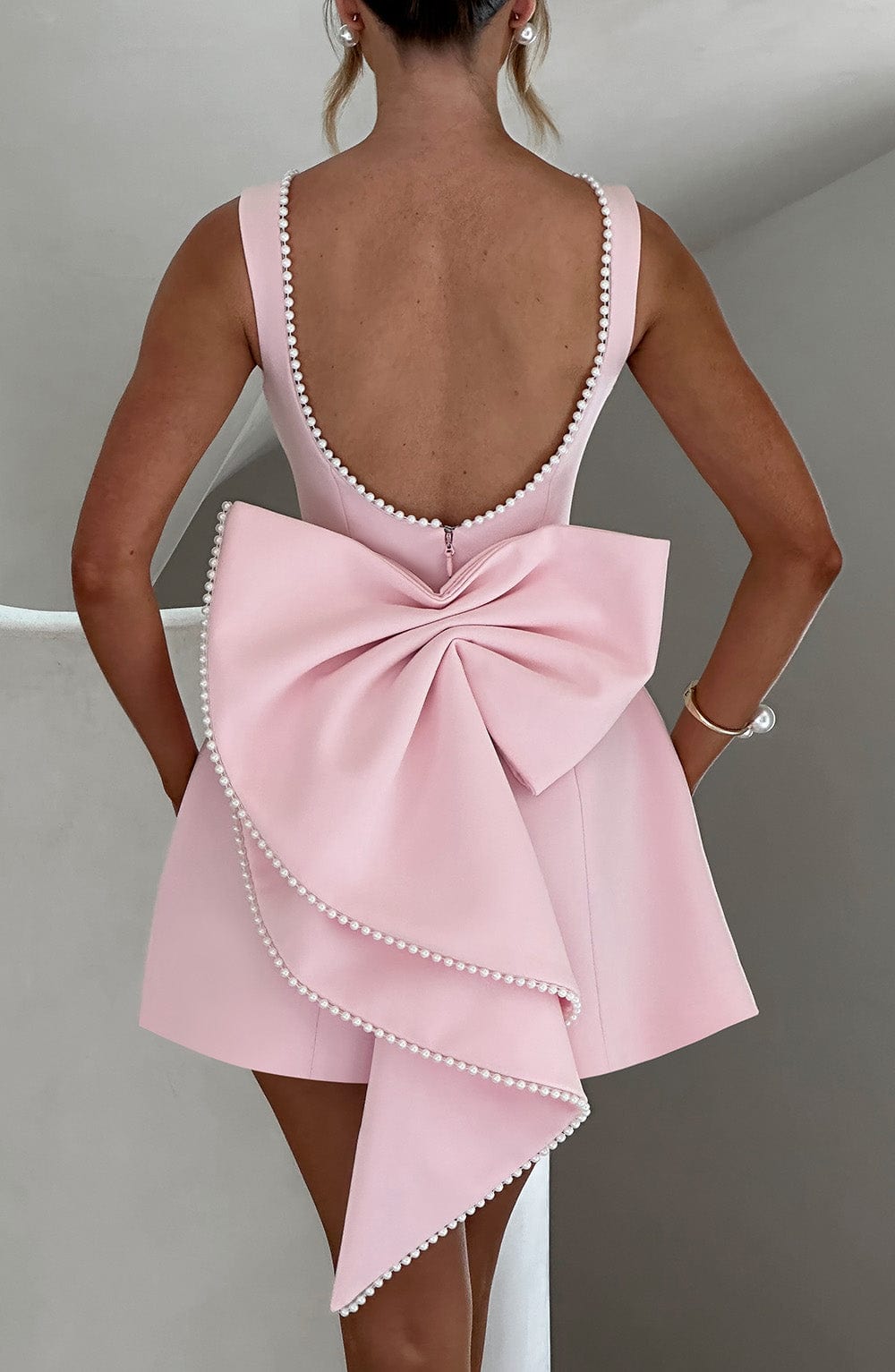 Female model in a wedding guest mini dress with a structured design and polished look.