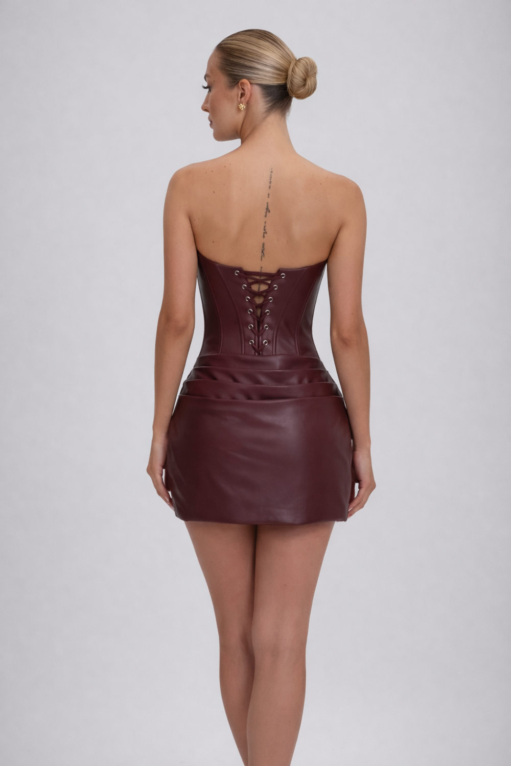 Female model wearing an evening mini dress on a plain background.