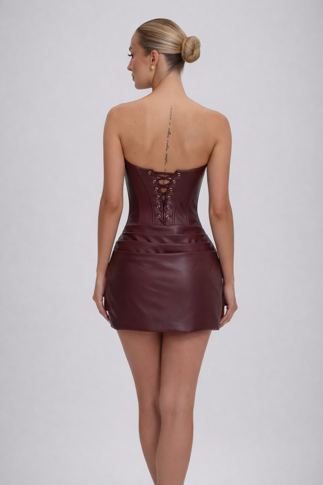 Female model wearing an evening mini dress on a plain background.