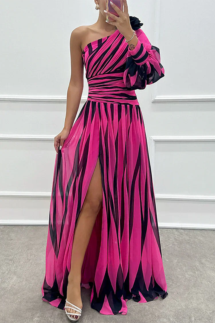 Woman standing in a striped dress with an asymmetrical neckline and pleated skirt.