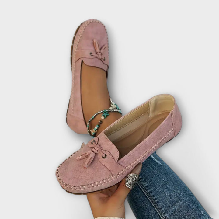 Pink loafers worn with blue jeans on a white background