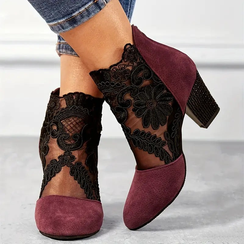 Mauve ankle boots with black lace detailing worn by a person.