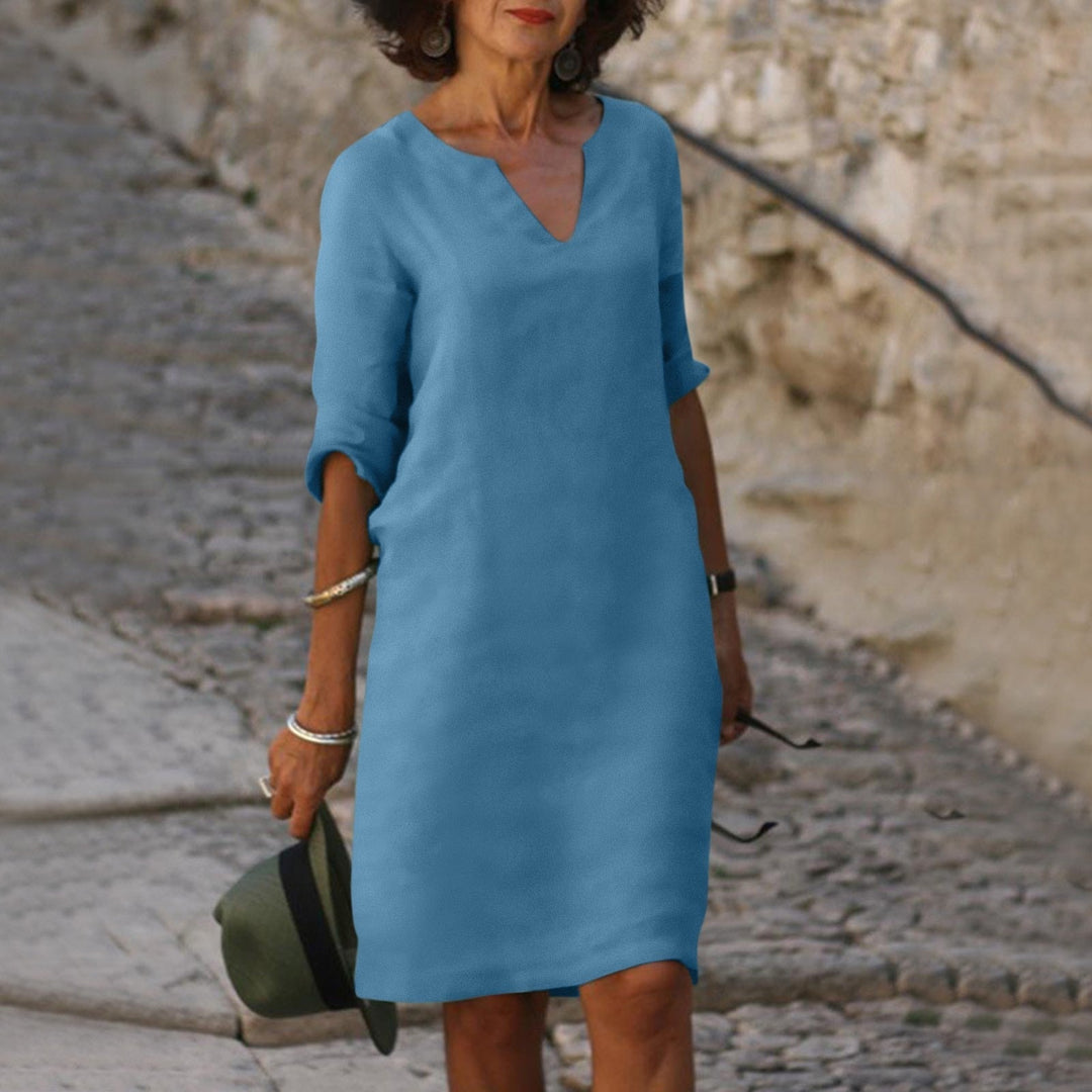 Woman model showcasing an everyday midi dress with simple V-neck styling on a clean background.