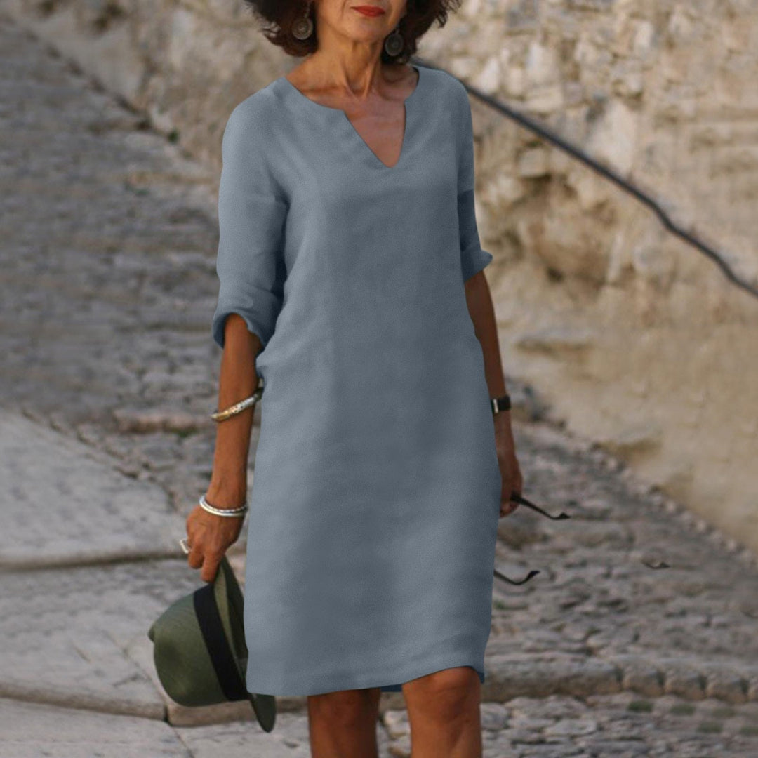 Woman model in a relaxed midi style dress with 3/4 sleeves on a clean background.
