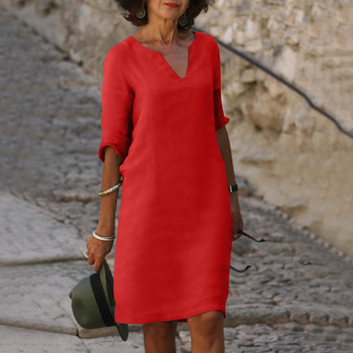 Woman model wearing a relaxed midi dress with V-neckline and 3/4 sleeves on a clean background.
