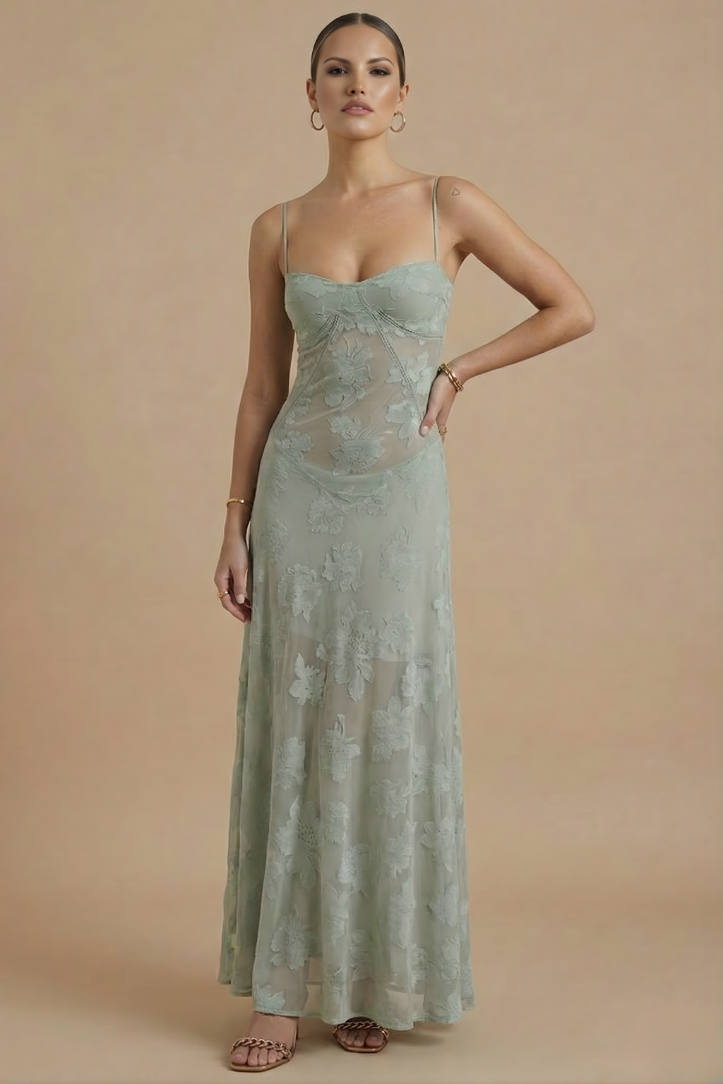 Female model wearing a long floral dress with delicate strap detail on a plain background.