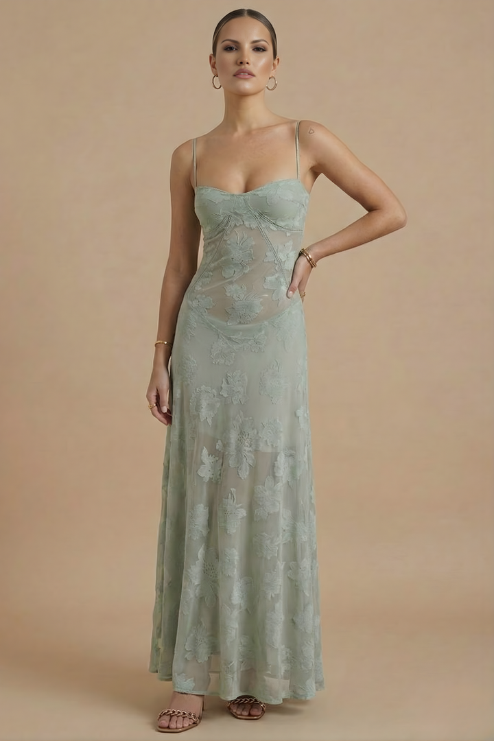 Female model wearing a long floral dress with delicate strap detail on a plain background.