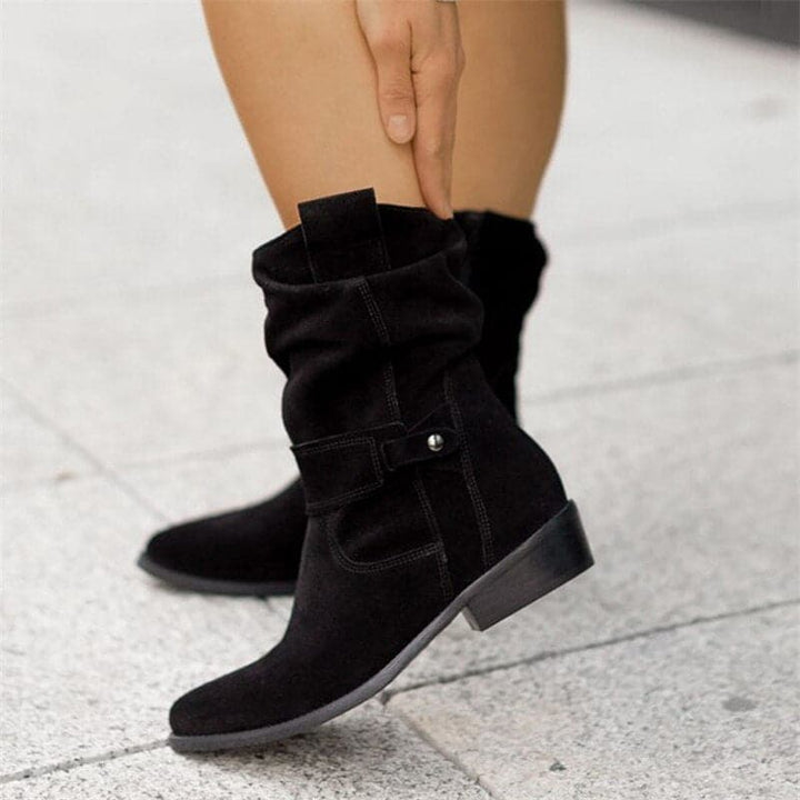 Black boots worn by a person on a light gray pavement.