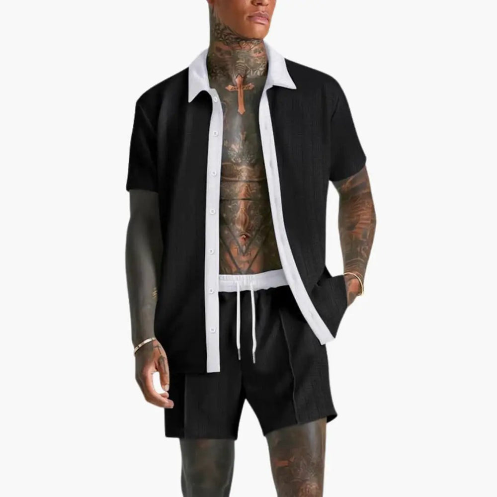  Model in a coordinated men’s short sleeve shirt and drawstring shorts set on a plain background.