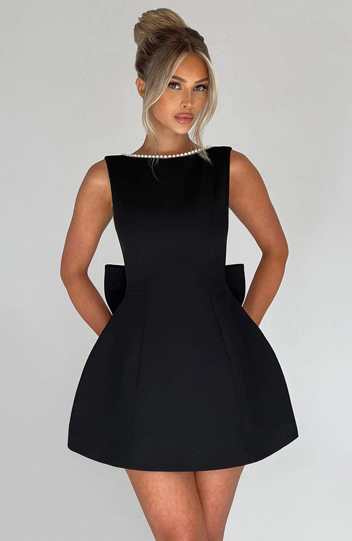Woman wearing a sleeveless structured mini dress against a plain backdrop.