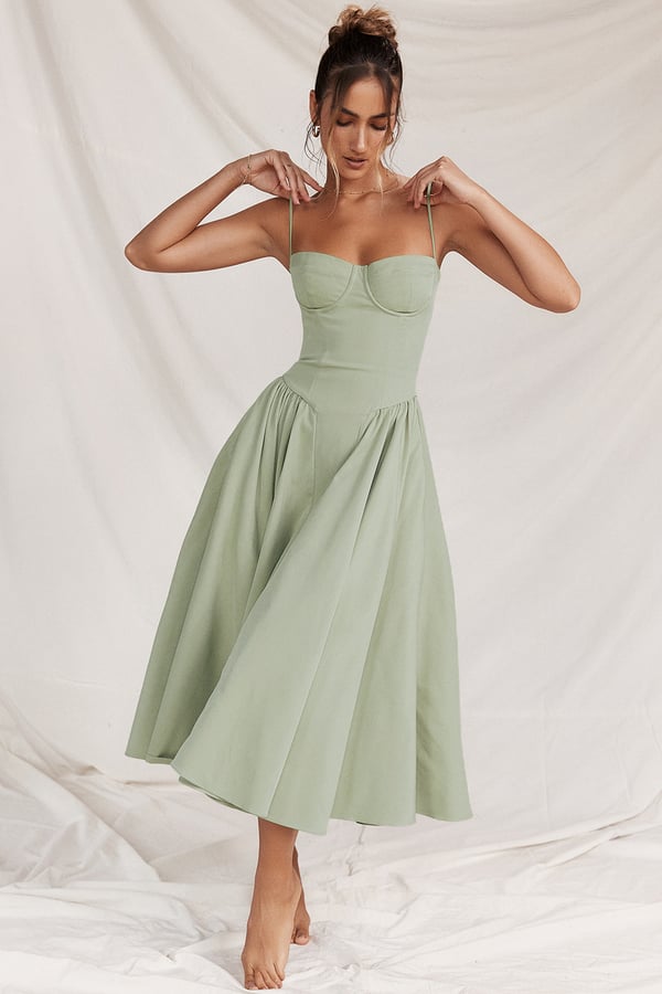 Female wearing a flowing midi dress on a plain background