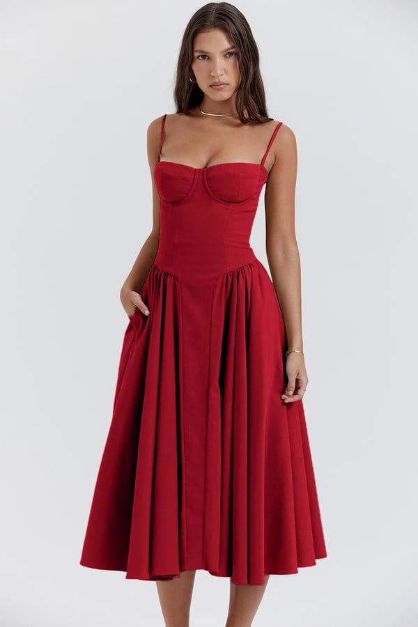 Female standing in an elegant pleated dress against a plain background